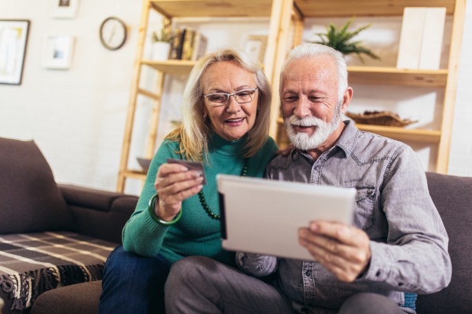 Älteres Ehepaar schaut auf ein Tablet.