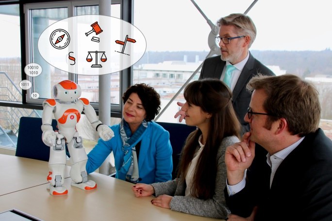 Vier Personen in einem Meeting-Raum diskutieren über einen humanoiden Roboter