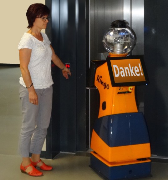 Eine Frau und ein Roboter vor einem Fahrstuhl