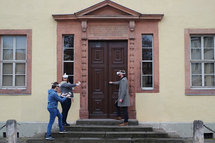 Drei Menschen mit VR-Brille vor einem Gebäude