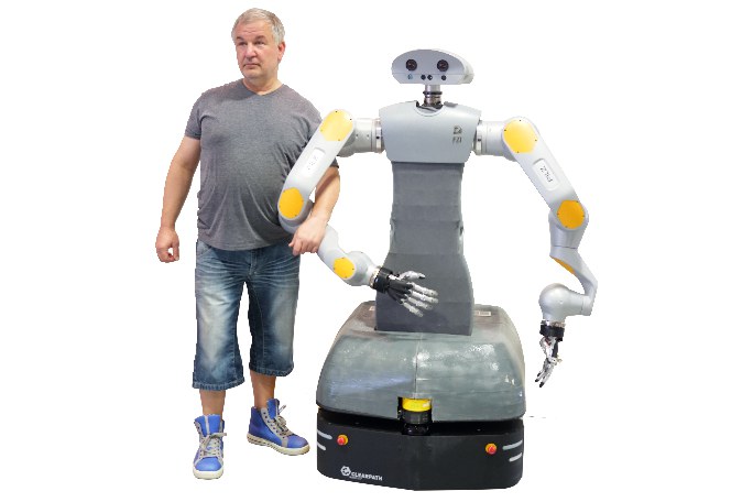 Ein Mann läuft mit untergehaktem Arm neben einem humanoider Roboter.