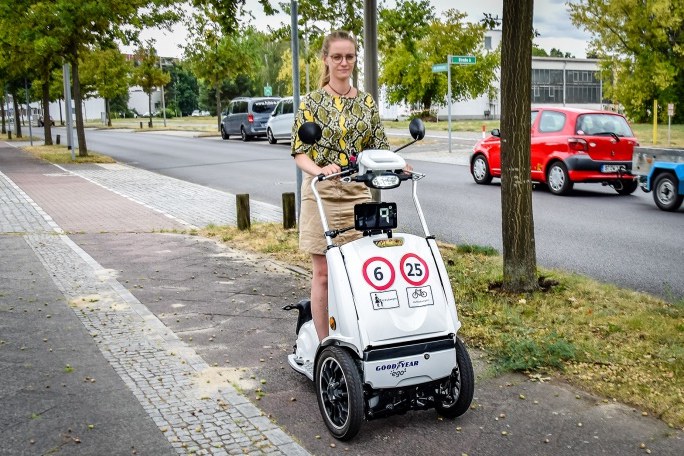 Eine Frau fährt mit einem Elektrokleindreirad auf dem Fahrradweg