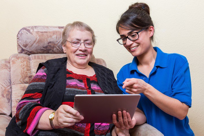 Schwester schaut mit Patientin auf Tablet