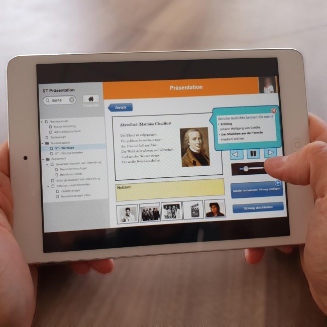 Bildschirm von einem Tablet wird groß dargestellt, auf dem man eine interaktive Präsentation sieht.