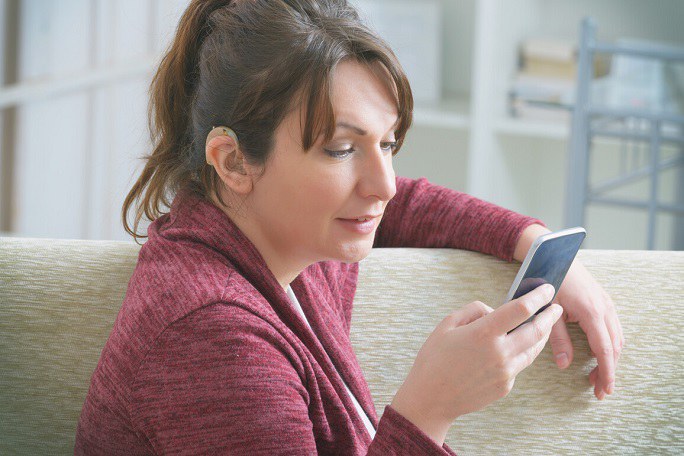 Frau mit Hörgerät benutzt Smartphone